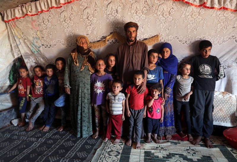 © Reuters. Ahmad Yassin al-Ali and his wife Fawza Umri pose for a picture with their children inside their tent, at Atmeh camp, near the Turkish border