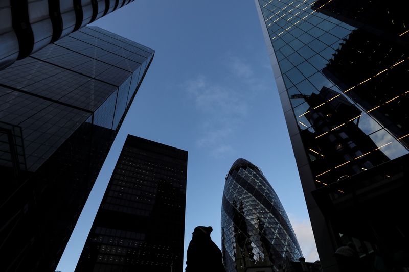 © Reuters. FILE PHOTO: A pedestrian walks past skyscrapers in the financial district in London