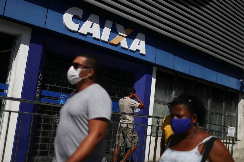 © Reuters. Pessoas com máscaras de proteção contra o coronavírus em frente a agência da Caixa no Rio de Janeiro (RJ)