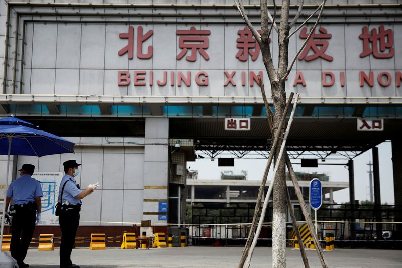 &copy; Reuters. Police officers wearing face masks stand guard outside an entrance to the Xinfadi wholesale market in Beijing