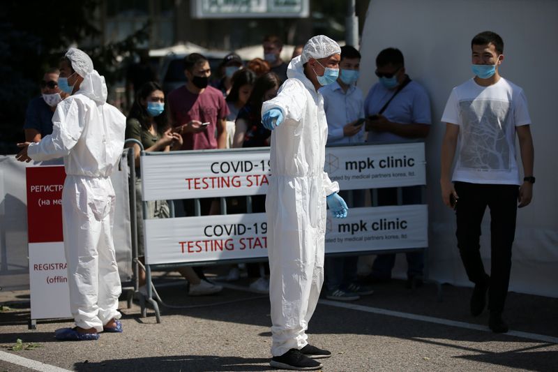 © Reuters. Люди ждут в очереди, чтобы пройти тестирование на коронавирус, в Алма-Ате