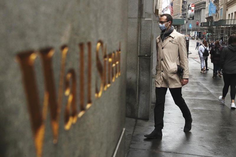 &copy; Reuters. Un uomo indossa una mascherina mentre passeggia lungo Wall Street durante l&apos;epidemia di coronavirus a New York