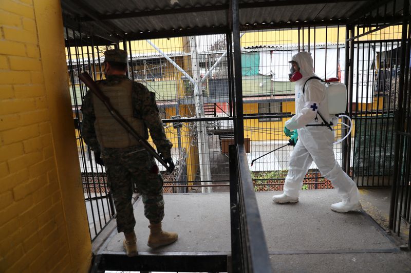 &copy; Reuters. Soldado chileno de guarda enquanto colega desinfecta local durante entrega de alimentos em comunidade carente de Santiago