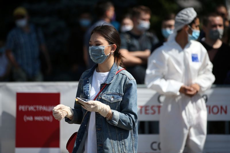 &copy; Reuters. Женщина в защитной маске на мобильной станции тестирования на коронавирус в Алма-Ате