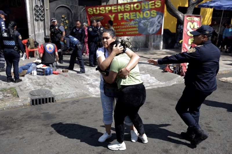 © Reuters. A woman is comforted by a friend after a relative was gunned down by unknown assailants outside a garage, in Mexico City