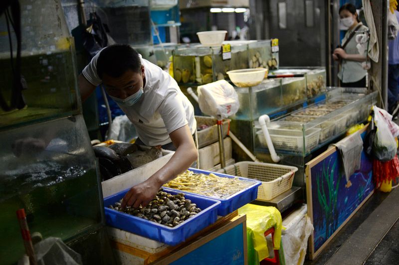 © Reuters. Los vendedores que usan una máscara facial están preparando mariscos en su puesto en el mercado mayorista de Yuegezhuang después de que ocurrieran nuevos casos de infecciones por la enfermedad por coronavirus (COVID-19) en Beijing