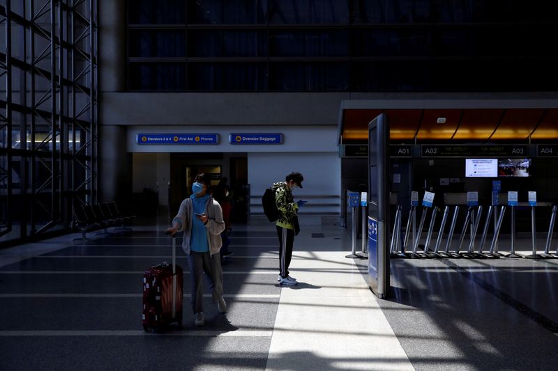 &copy; Reuters. FILE PHOTO: Passengers wear protective face masks at Los Angeles International Airport (LAX) on an unusually empty Memorial Day weekend during the outbreak of the coronavirus disease (COVID-19) in Los Angeles