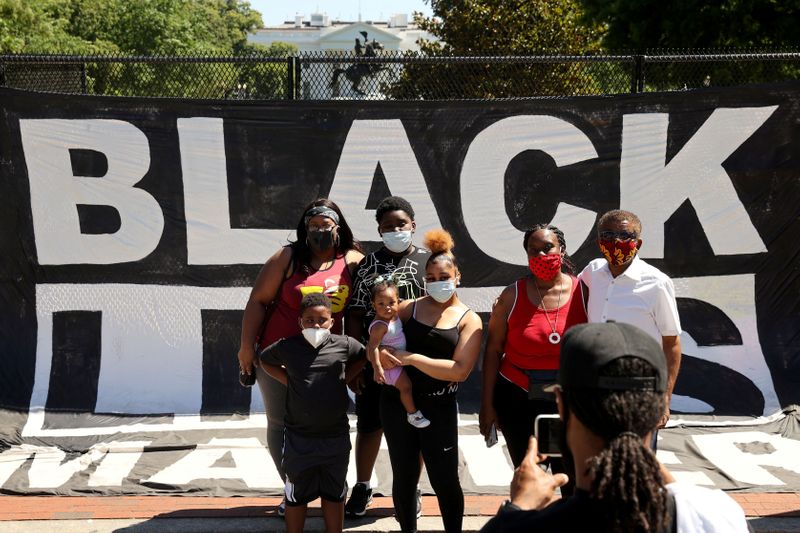 © Reuters. A family stops to take a picture at the fence around Lafayette Square to view the scene where protesters clashed with police near the White House in Washington