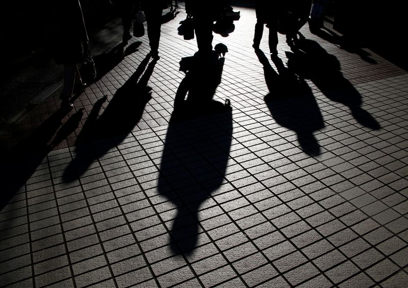 &copy; Reuters. Pedestrians cast shadows as they make their way at a financial district in Tokyo