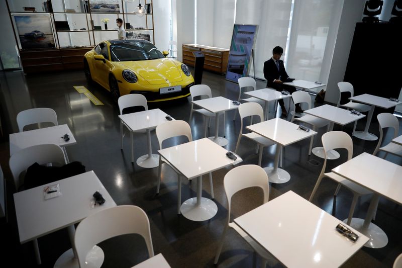 &copy; Reuters. A man sits in front of a Porsche 911 sports car on display at its dealership during a news conference in Seoul