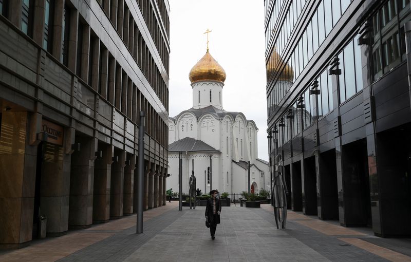 &copy; Reuters. A woman wearing a protective face mask walks walks in a business district in Moscow