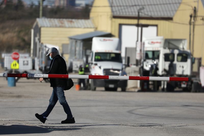 © Reuters. A man wearing a face mask walks past the entry gate at the Maple Lodge Farms chicken processing plant in Brampton