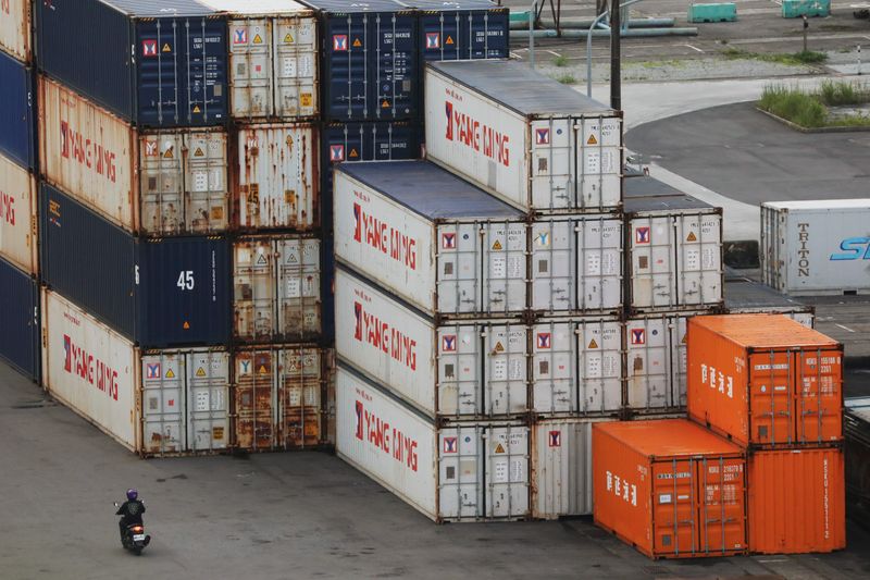 &copy; Reuters. A person drives a motorcycle by shipping containers at a port in Keelung