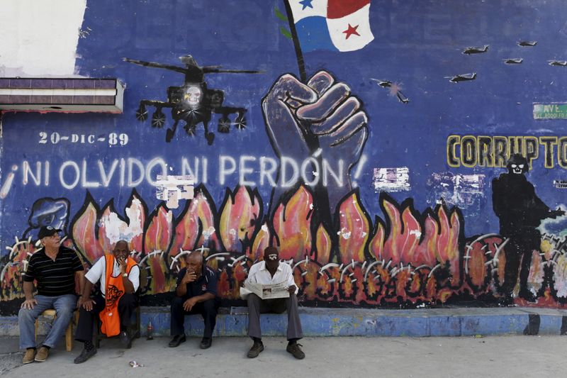 &copy; Reuters. Foto de archivo ilustrativa de un hombre leyendo un diario con la foto del exdictadoe panameño Manuel Noriega sentado frente a un graffiti alusivo a la invasión de EEUU