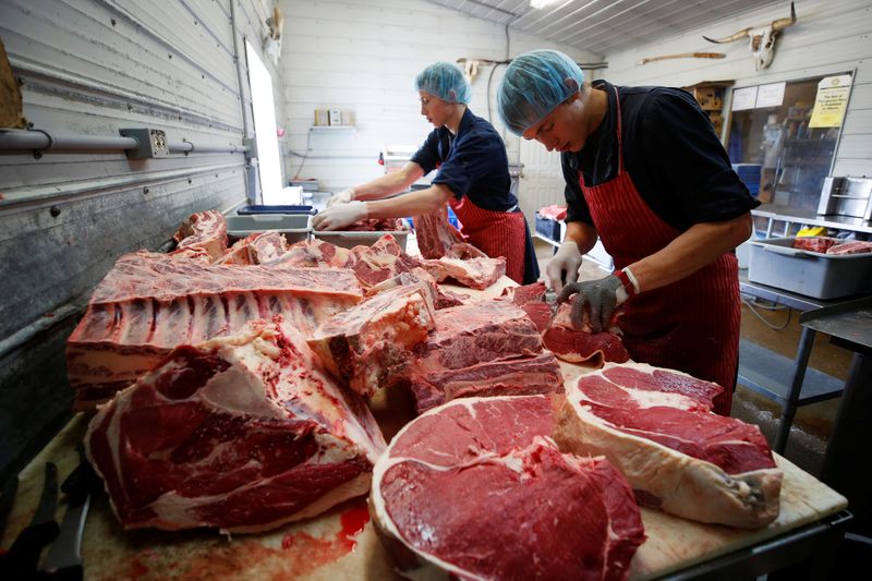 © Reuters. Butchers Allan and Gerald vande Bruinhorst work on a beef carcass in Picture Butte