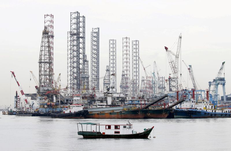 © Reuters. FILE PHOTO: Offshore drilling platforms (rear) stand together at a dock yard near Singapore port