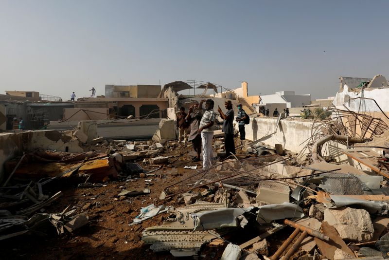 &copy; Reuters. FILE PHOTO: People stand on a roof of a house amidst debris of a passenger plane, crashed in a residential area near an airport in Karachi