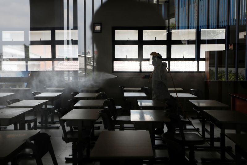 © Reuters. Personal de la Cruz Roja de Indonesia con desinfectantes en aerosol para equipo de protección en un aula de una escuela en Yakarta