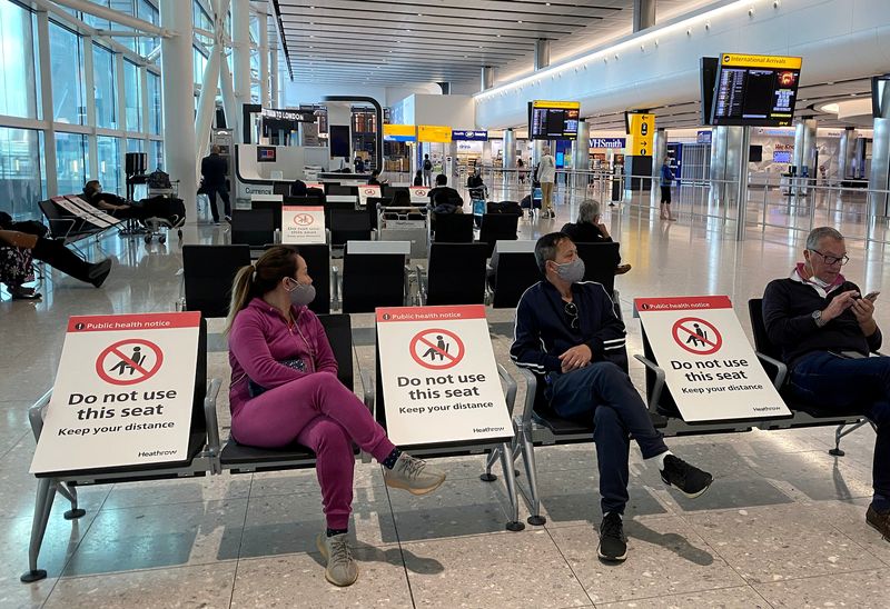 &copy; Reuters. FILE PHOTO: People sit amongst socially-distanced seating signs at Heathrow Airport in London
