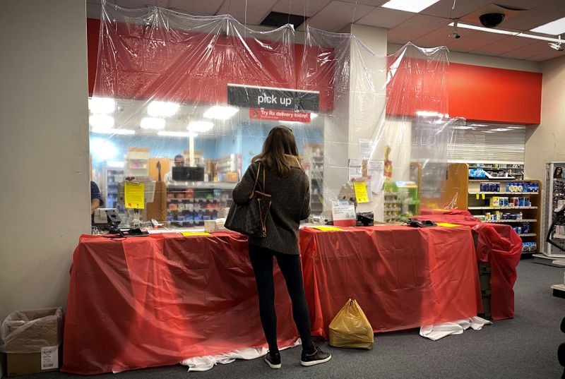 &copy; Reuters. FILE PHOTO: Woman waits behind a sheet of protective plastic at the pharmacist&apos;s counter at a CVS Pharmacy during the outbreak of coronavirus disease (COVID-19) in New York