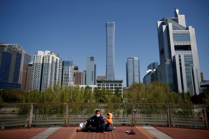 &copy; Reuters. FOTO DE ARCHIVO: Un hombre y un niño se sientan en un parque cerca del Distrito Central de Negocios en Pekín en China, el 22 de abril de 2020