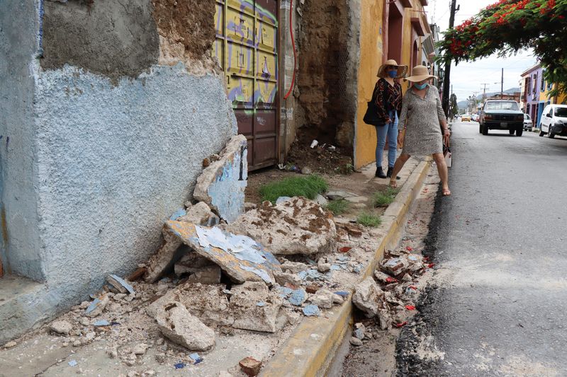 © Reuters. Women walk by a building damaged during a quake, in Oaxaca