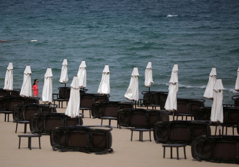 &copy; Reuters. Tourist walks near empty sunbeds at Sunny Beach resort on the Black Sea