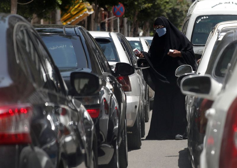 &copy; Reuters. FILE PHOTO: A woman wearing a protective face mask, amid concerns over the coronavirus disease (COVID-19) asks for money at a traffic jam in central Cairo