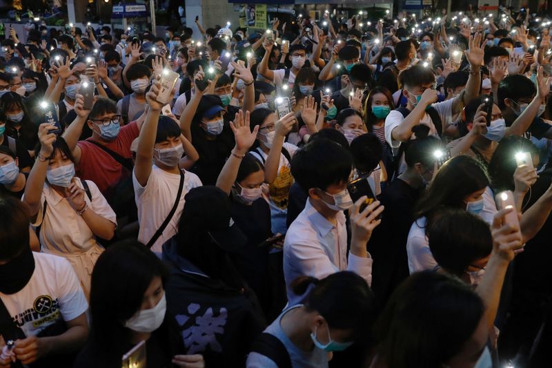 &copy; Reuters. Pro-democracy demonstrators march holding their phones with flashlights on during a protest to mark the first anniversary of a mass rally against the now-withdrawn extradition bill, in Hong Kong