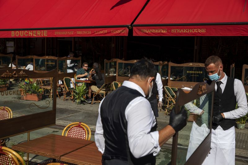 © Reuters. Waiters at a restaurant adjust social distancing screens outside for outdoor seating a restaurant in New York City