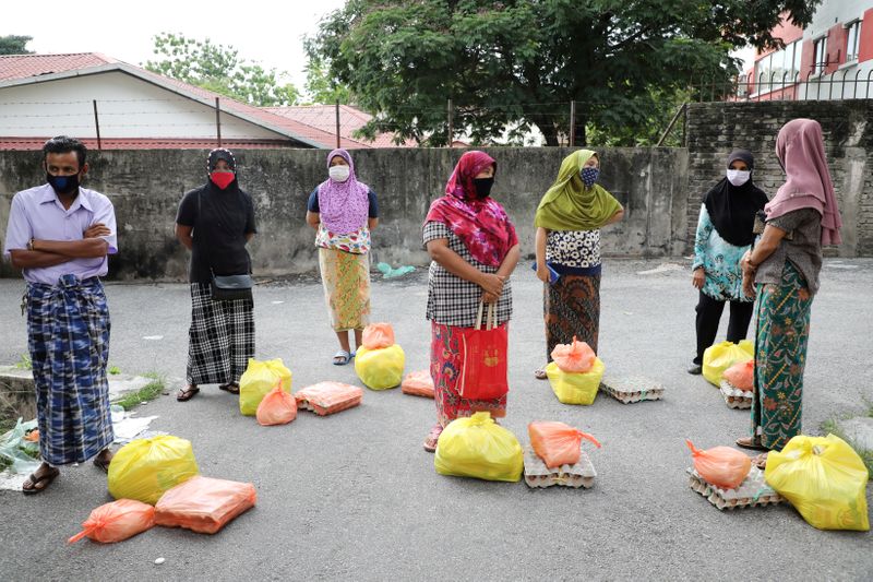 &copy; Reuters. FILE PHOTO: Rohingya refugees wearing protective masks keep a social distance while waiting to receive goods from volunteers, during the movement control order due to the outbreak of the coronavirus disease (COVID-19), in Kuala Lumpur