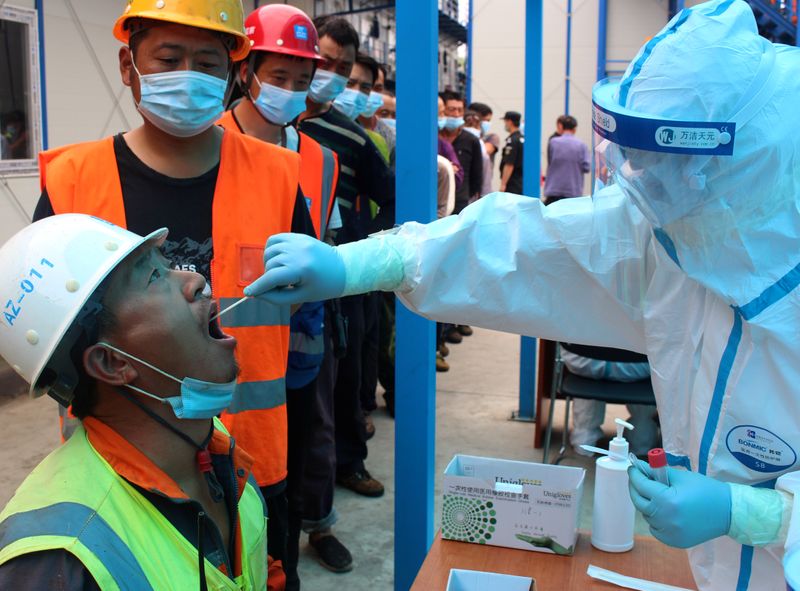 © Reuters. FILE PHOTO:  Medical worker collects swabs from construction workers for nucleic acid tests in Beijing