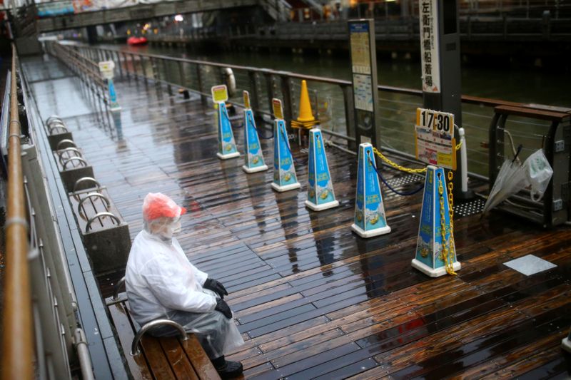 &copy; Reuters. A worker, wearing protective mask following an outbreak of the coronavirus disease (COVID-19), waits for receives tourists on an almost empty pier in the Dotonbori entertainment district of Osaka