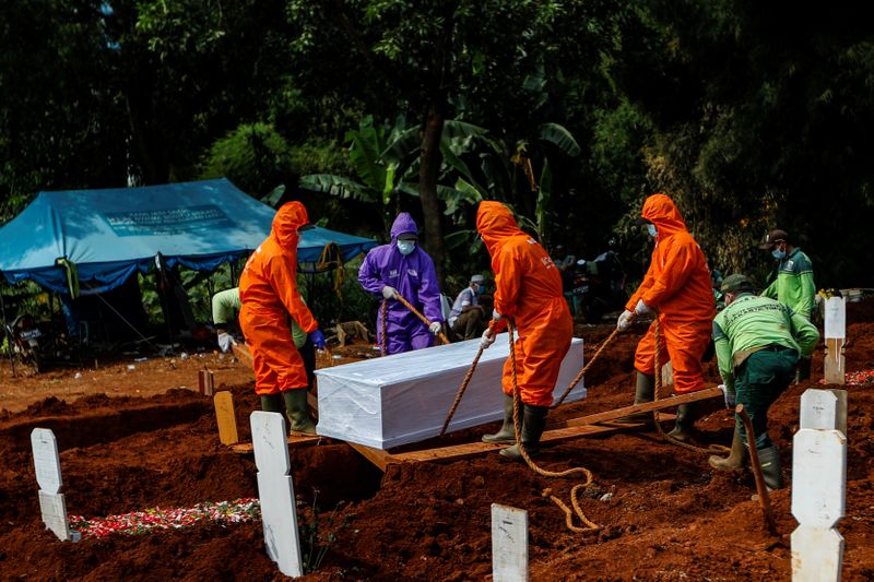 &copy; Reuters. Люди в защитных костюмах на кладбище для жертв коронавируса в Джакарте