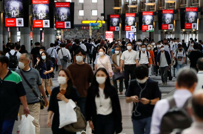 &copy; Reuters. Diverse persone camminano per le strade di Tokyo, indossando maschere protettive