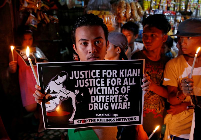 &copy; Reuters. FILE PHOTO: Protesters and residents hold lighted candles and placards at the wake of Kian Loyd delos Santos, a 17-year-old high school student, who was among the people shot dead last week in Manila