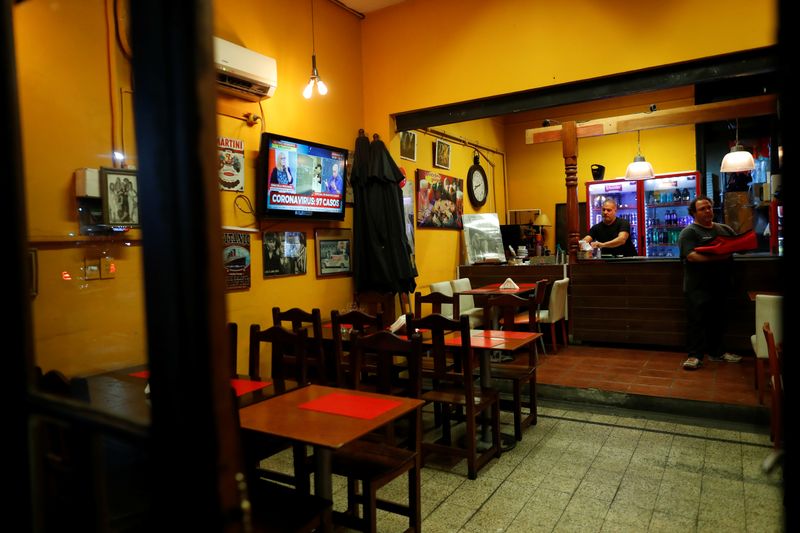 &copy; Reuters. Employees work in a pizza shop as TV announces 97 confirmed cases of the coronavirus disease (COVID-19), in Buenos Aires