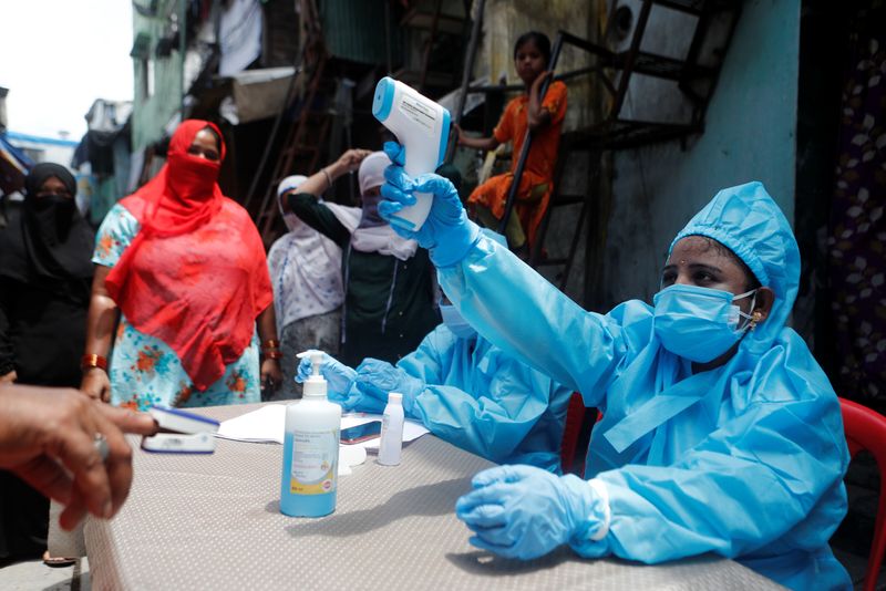 &copy; Reuters. Profissional de saúde em trajes de proteção checa temperatura de morador em área de favela em Mumbai, na Índia