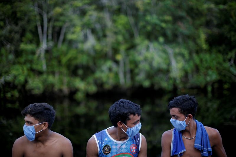 © Reuters. Indígenas com máscaras de proteção contra Covid-19 conversam enquanto agentes de saúde checam moradores de aldeia no Pará
