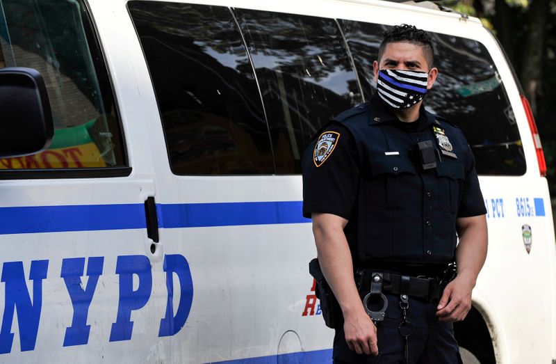 &copy; Reuters. A NYPD police offer wears a Blue Line facemask at the scene of a shooting