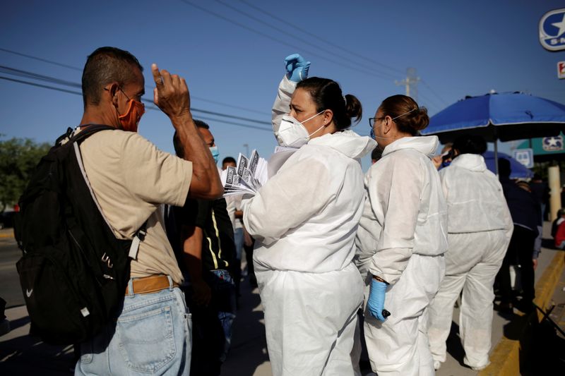 © Reuters. Personnel of an assembly factory, in protective gear, talk to job seekers as the coronavirus disease (COVID-19) outbreak continues in Ciudad Juarez