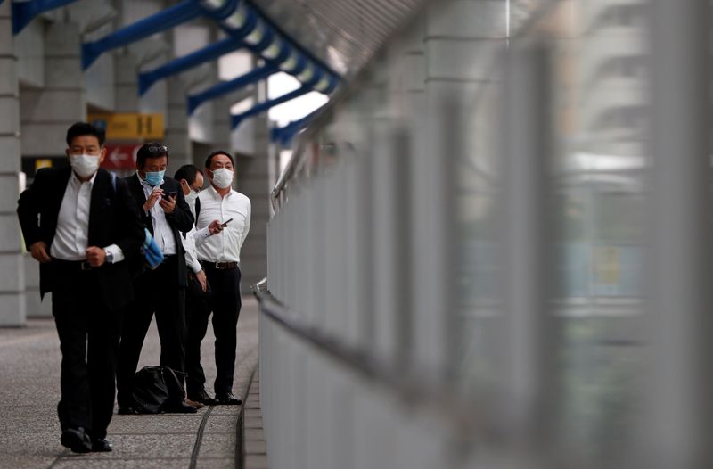 &copy; Reuters. Businessmen wearing protective face masks are seen on a pedestrian bridge in a business district in Tokyo