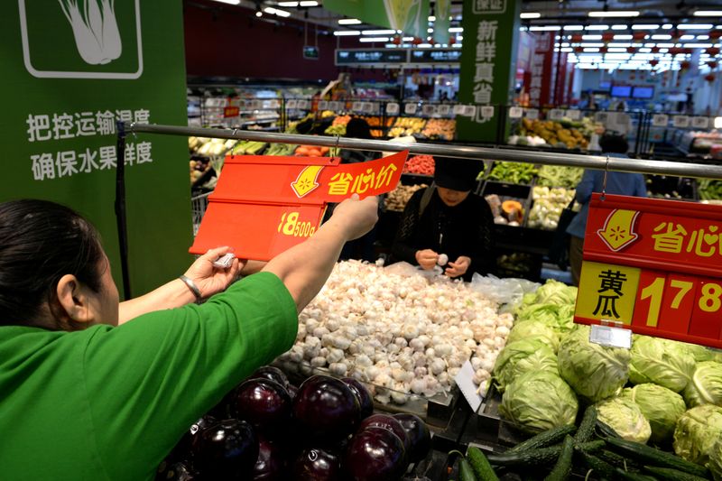 &copy; Reuters. FILE PHOTO: Staff member inserts a price tag for vegetable at a Walmart in Beijing