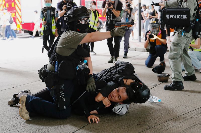 © Reuters. A police officer raises his pepper spray handgun as he detains a man during a march against the national security law at the anniversary of Hong Kong's handover to China from Britain in Hong Kong