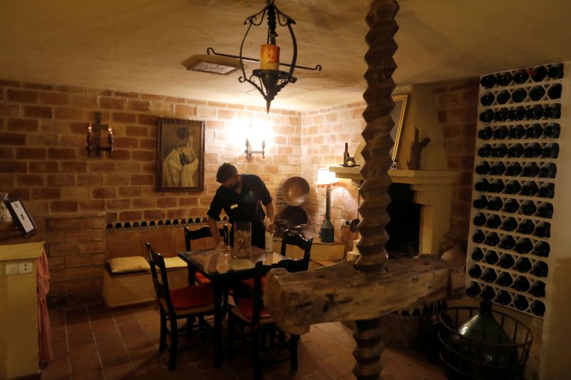 © Reuters. FILE PHOTO: A waiter wears a protective face mask as he disinfects a table at a wine cellar room of the Soho Boutique Palacio San Gabriel hotel after an easing of restrictions imposed to control the spread of the coronavirus disease (COVID-19), in downtown