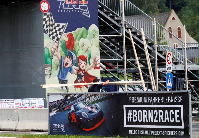 © Reuters. A worker passes a poster next to the Formula One race track in Spielberg