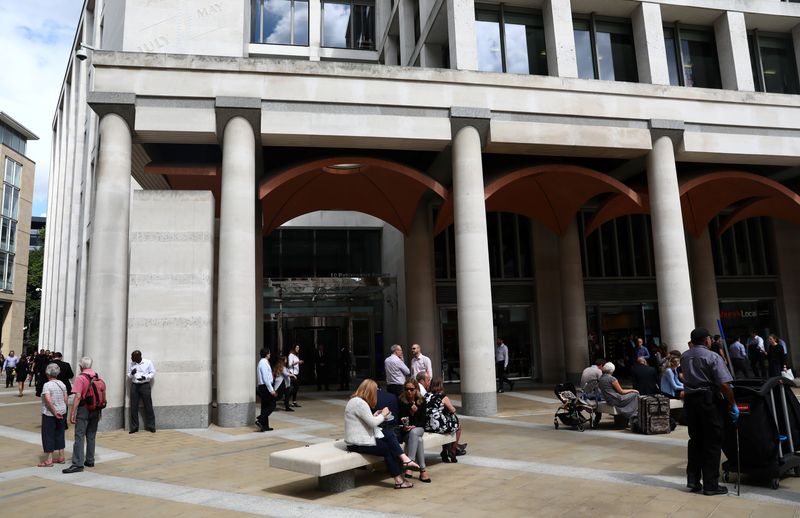 &copy; Reuters. People stand and sit outside the London Stock Exchange in Paternoster Square, London