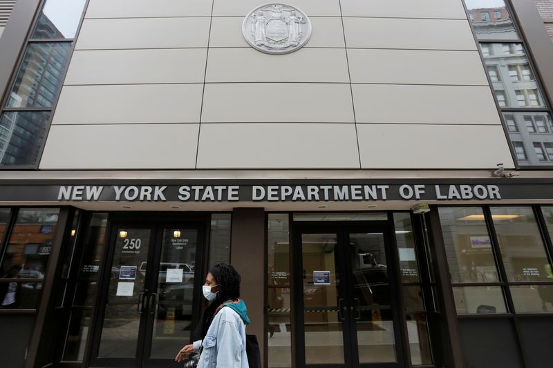 &copy; Reuters. Un passante davanti all&apos;ingresso degli uffici del Dipartimento del Lavoro dello Stato di New York