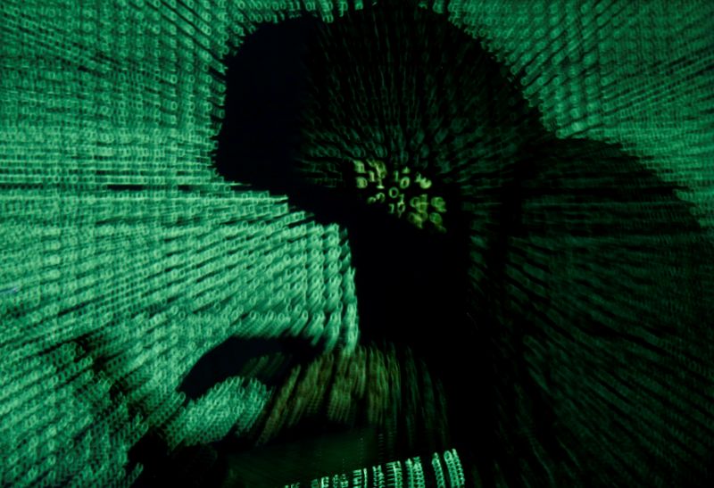 © Reuters. FOTO DE ARCHIVO: Un hombre sostiene un ordenador portátil mientras se proyecta un código cibernético sobre él en esta foto ilustrativa tomada el 13 de mayo de 2017