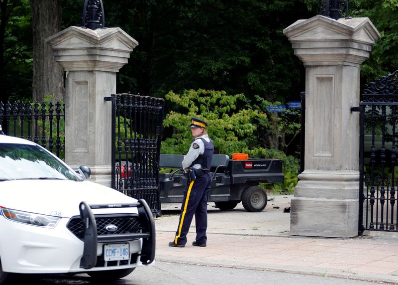 © Reuters. A police officer stands near a damaged gate at Rideau Hall in Ottawa